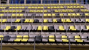 Parlak sarı ve soluk gri renklerle süslenmiş boş stadyum koltukları gösterişli modern bir tasarımı temsil ediyor.