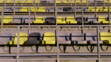 Parlak sarı ve soluk gri renklerle süslenmiş boş stadyum koltukları gösterişli modern bir tasarımı temsil ediyor.