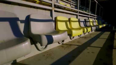 Parlak sarı ve soluk gri renklerle süslenmiş boş stadyum koltukları gösterişli modern bir tasarımı temsil ediyor.