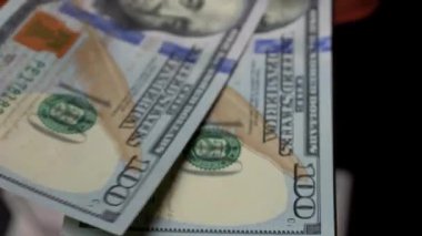 Eller titizlikle koyu bir yüzeye serilmiş sayısız dolarlık banknotları sayıyor.