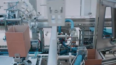 Görüntü, büyük bir üretim tesisinde etkin bir şekilde çalışan yüksek teknolojili otomatik ambalaj hattını gösteriyor.