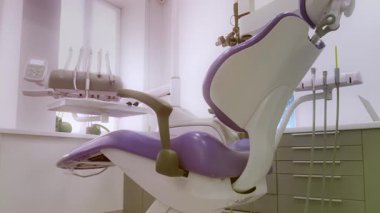 Parlak, temiz bir klinik ortamında gelişmiş diş teknolojisi sunan gösterişli, modern bir dişçi koltuğu..
