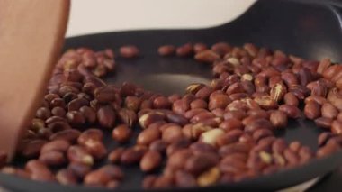 Tavada kızartılan çiğ kahve çekirdekleri odaklı bir çekim, tüm kızartma sürecini zengince vurguluyor.