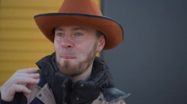 Kendine güvenen, kendine özgü kovboy şapkası takan bir adam renkli bir arka plana cesur ve çarpıcı bir poz veriyor.