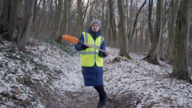Soğuk için tam teçhizatlı bir insan, elinde bir kürek tutarken güvenli bir şekilde karlı bir ormanda poz verir.