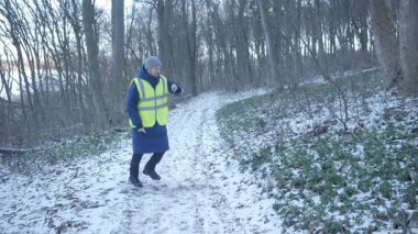 Güzel bir karlı ormanda parlak yansıtıcı yelek giyen bir birey kış boyunca doğayla derin bir ilişki içindedir.