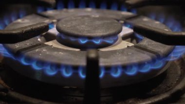 Isı ve pişirme enerjisini gösteren canlı mavi alevleri gösteren bir gaz ocağının detaylı bir yakın çekimi.