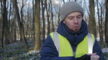 Güzel bir karlı ormanda parlak yansıtıcı yelek giyen bir birey kış boyunca doğayla derin bir ilişki içindedir.