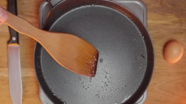 Ahşap bir kaşık, bir tava ve lezzetli tarifler için bir yumurta kullanarak yemek yapmaya hazırlanıyorum.