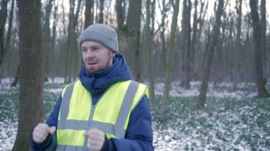 Güzel bir karlı ormanda parlak yansıtıcı yelek giyen bir birey kış boyunca doğayla derin bir ilişki içindedir.