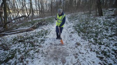 Güzel bir karlı ormanda parlak yansıtıcı yelek giyen bir birey kış boyunca doğayla derin bir ilişki içindedir.