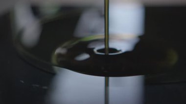 Parlak bir yüzeye dökülen yağın yakın çekim görüntüsü pürüzsüz dokusunu ve zengin akışını gözler önüne seriyor.