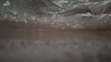 Geniş su birikintilerinde sıçrayan, dinamik yağmurlu havayı gösteren bir botun ayrıntılı ve canlı bir görüntüsü.