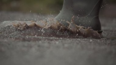 Geniş su birikintilerinde sıçrayan, dinamik yağmurlu havayı gösteren bir botun ayrıntılı ve canlı bir görüntüsü.