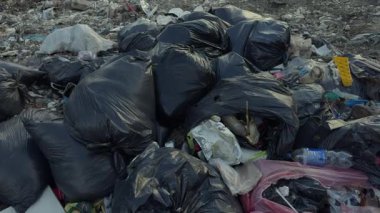 Kentsel bir alanda yol kenarındaki siyah çöp torbaları atık yönetimi sorunlarını vurguluyor..