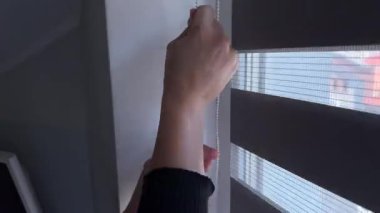 A person skillfully adjusting roller blinds in a stylish and contemporary interior, enhancing the flow of natural light