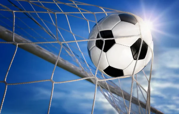 サッカーやサッカーのゴールは 古典的なデザインのボールは ネットに飛んで 背景に青い空と太陽と — ストック写真