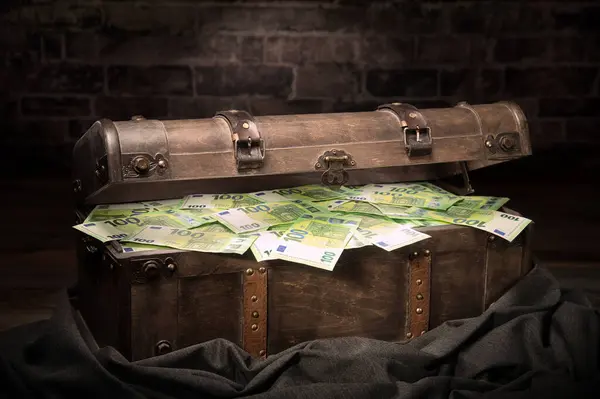 Vintage big treasure box filled with Euro cash hidden in a secretive room. A neat concept for finance, money, wealth, winning, corruption, secrecy and more.