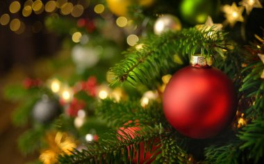 Süslü bir köknar ağacına asılı kırmızı bir noel takısı, bir sürü parlak süs ve ışıkla birlikte