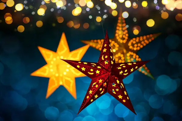 stock image Hanging Christmas lantern stars with abstract blurred lights. Three illuminated ornamental pieces on dark blue background with festive bokeh highlights