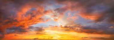 Gün batımında çarpıcı bir şekilde parlayan gökyüzü turuncu görkemli bulutlarla aydınlandı. Canlı bir panoramik bulut manzarası fotoğrafı..