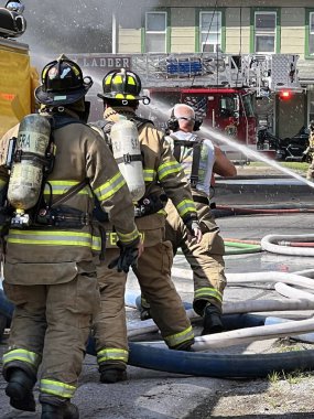 Acil durum görüntülendi. Oksijen tanklarıyla tam teçhizatlı itfaiyeciler sokakta bekliyor. İtfaiyeciler yangını söndürmek için su püskürtüyorlar. İtfaiye araçları, hortumlarla birlikte etraflarını sardı..