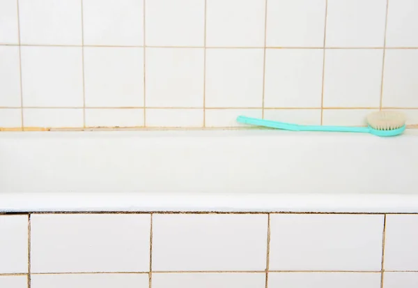 浴槽と白いタイルとバスブラシ付きの古いバスルームのインテリア — ストック写真