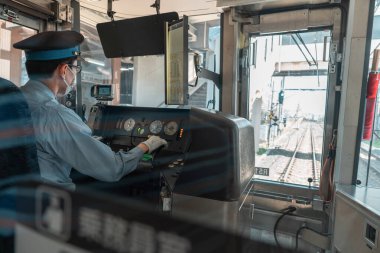 Asyalı erkek tren şoförü iş yerinde, arkadan manzaralı.