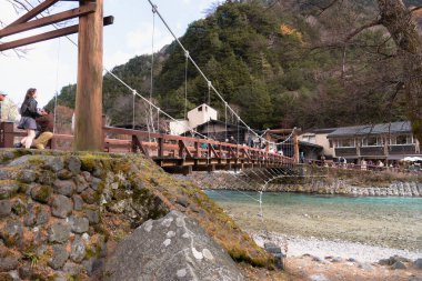 Nagano, JAPAN - 12 Kasım 2024: Kappa Bashi Köprüsü Azusa Nehri 'nin açık suları üzerinde dağlar ve gökyüzü Kamikochi, Nagano Bölgesi, Japonya