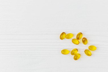 Yağ yumuşak kapsülleri beyaz ahşap masa üzerinde, üst görünüm