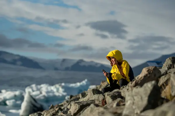Sarı Ceketli Gezgin Cep telefonuyla Kuzey Kutbu Sahnesinin tadını çıkarıyor