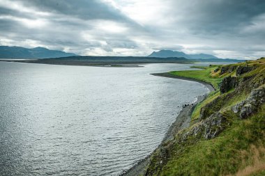 Bulutlu Gökler Altında Dağ Manzaralı Huzurlu Lakeside Kayalıkları