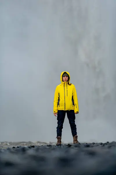 Sarı ceketli kız şelalenin arka planında