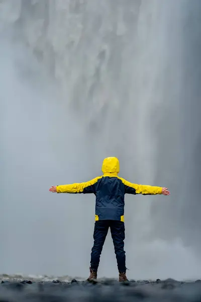 Sarı ceketli kız şelalenin arka planında