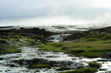 Geothermal Hot Springs in Lush Green Icelandic Landscape with Rising Steam clipart