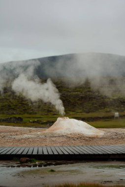 Geothermal Hot Spring Landscape with Rising Steam and Barren Terrain clipart