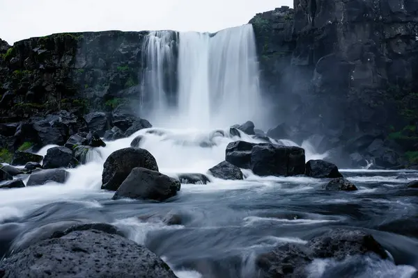 Şelale taşların üzerine dökülüyor.