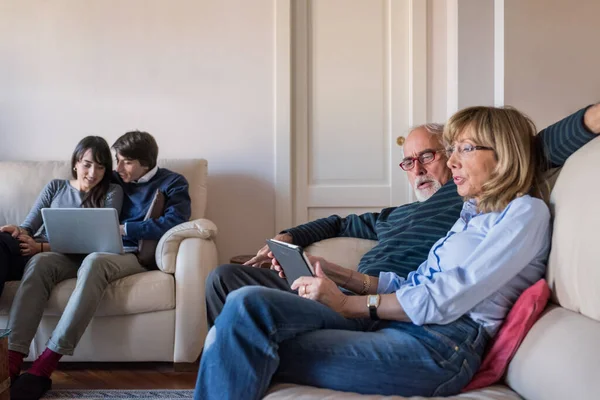 シニア成熟したカップル座ってソファ屋内でホーム使用してタブレットコンピュータ — ストック写真