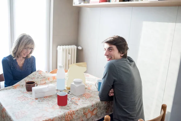 2人の大人の母親と息子屋内でホームキッチンで朝食を一緒に笑顔 — ストック写真