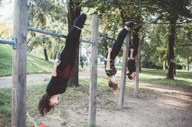 Üç atletik arkadaş açık hava fitness parkında güç ve denge için birlikte egzersiz yapıyorlar.