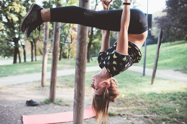 在室外健身园练习杂技瑜伽以获得力量和平衡的体格健壮的年轻女子 — 图库照片