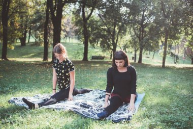 Spor yapmadan önce dışarıda uzanan iki genç kadın.