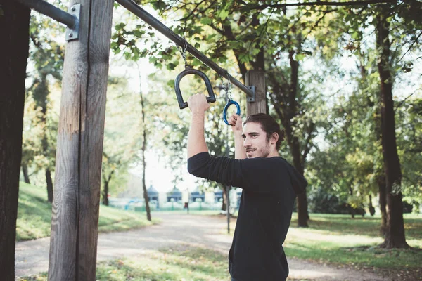 スポーツリング屋外設備の整った公園でのトレーニングのために準備運動若い男をフィット — ストック写真