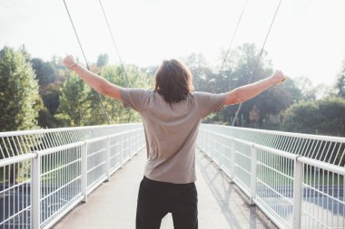 Genç atletik adam kollarını açık havada güneşlenmenin tadını çıkarıyor. 