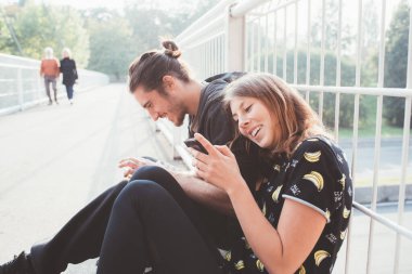 Formda bir çift spor sonrası eğleniyor gülümseyerek ve akıllı telefon kullanarak eğleniyor.