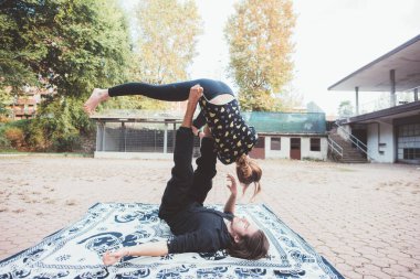 Sağlıklı genç adam, çimenleri dengede tutan akrobatik yoga yapan bir kadın.