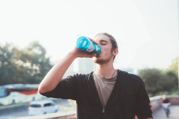 市内の屋外で再利用可能なボトルから若い男飲料水を行使することから休憩を取って肖像画 — ストック写真
