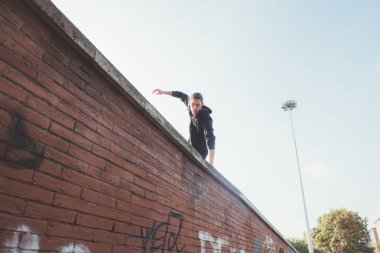 Acrobatic stunt man outdoors doing parkour training trick jumping above obstacle running