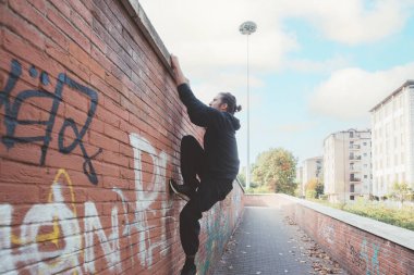 Athletic acrobatic stuntman doing parkour trick training outdoors