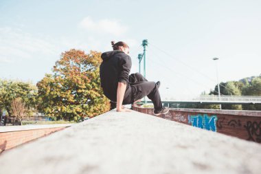 Akrobatik atletik sporcu genç adam engellerin üzerinden atlayıp antrenman parkına gidiyor.